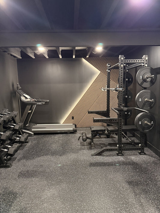 Finished basement home gym in Walled Lake, MI with half rack, bumper plates, adjustable bench and treadmill